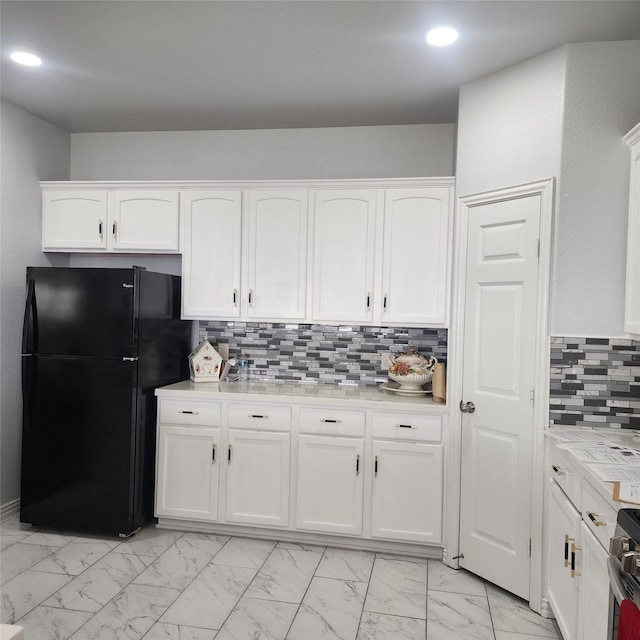 kitchen with light countertops, marble finish floor, tasteful backsplash, white cabinetry, and freestanding refrigerator