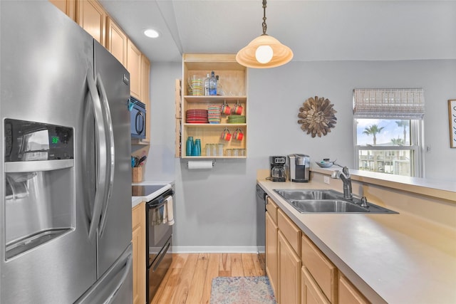 kitchen with pendant lighting, light countertops, light brown cabinets, a sink, and black appliances