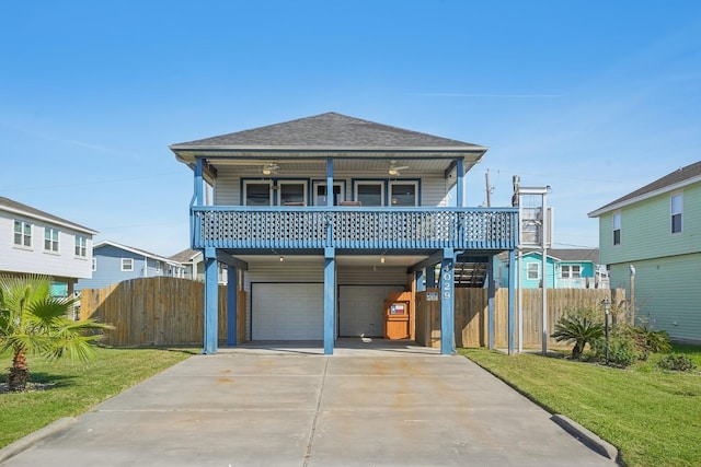 beach home with a garage, covered porch, roof with shingles, a carport, and a front lawn