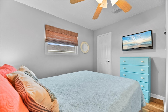 bedroom with baseboards, visible vents, ceiling fan, and wood finished floors