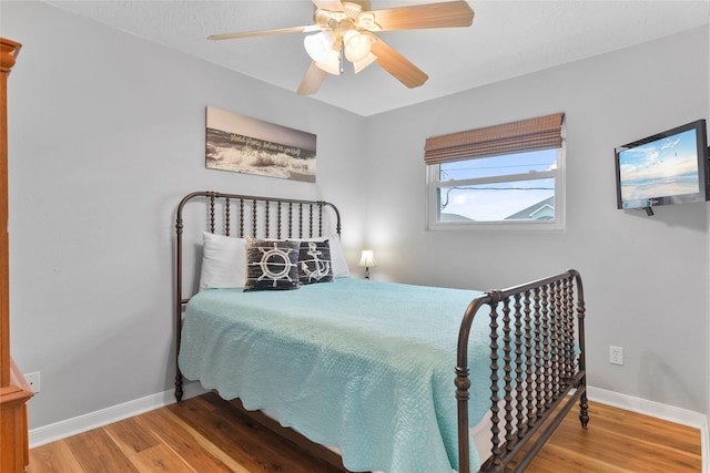 bedroom featuring a ceiling fan, baseboards, and wood finished floors