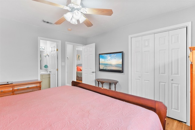 bedroom with light wood finished floors, visible vents, a ceiling fan, ensuite bath, and a closet