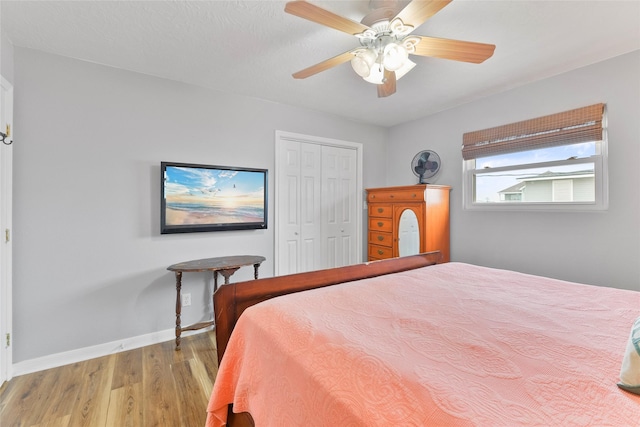 bedroom with light wood finished floors, a closet, a ceiling fan, and baseboards