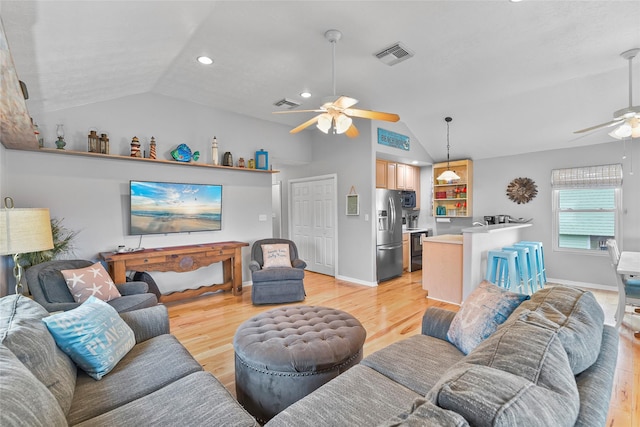 living area featuring visible vents, baseboards, ceiling fan, vaulted ceiling, and light wood-type flooring