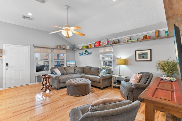 living room with a ceiling fan, visible vents, vaulted ceiling, and wood finished floors