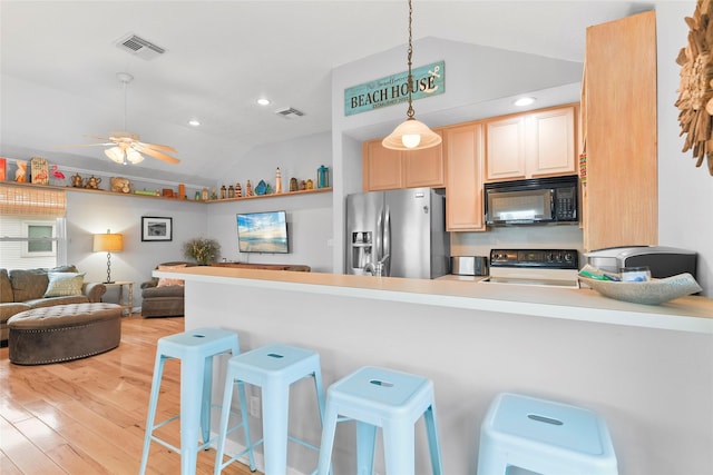 kitchen with black microwave, range with electric stovetop, open floor plan, stainless steel fridge, and decorative light fixtures