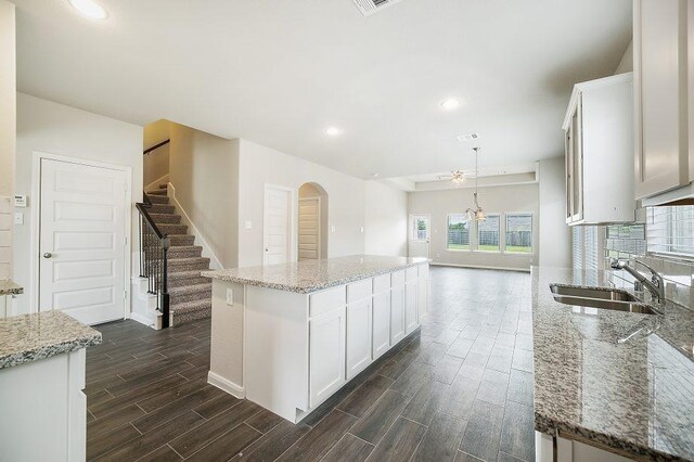 kitchen with a center island, white cabinetry, a sink, and hanging light fixtures