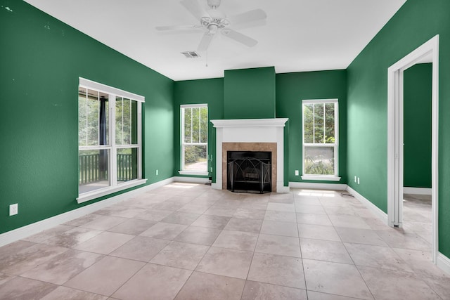 unfurnished living room with a wealth of natural light, baseboards, and a tiled fireplace