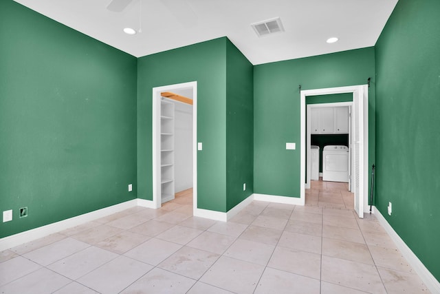 unfurnished bedroom featuring light tile patterned floors, visible vents, baseboards, a spacious closet, and independent washer and dryer