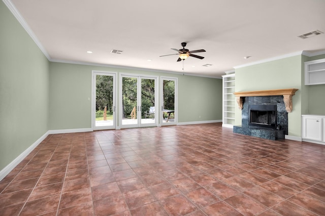 unfurnished living room with built in shelves, a ceiling fan, a high end fireplace, baseboards, and ornamental molding