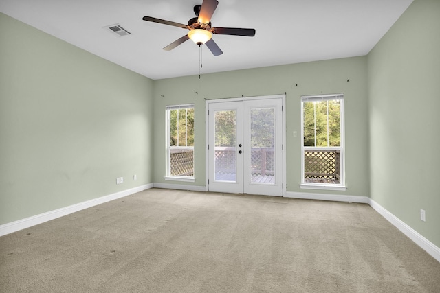 spare room with baseboards, a wealth of natural light, visible vents, and light colored carpet