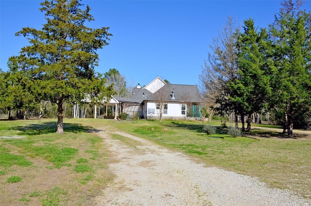 view of front of property with dirt driveway and a front lawn