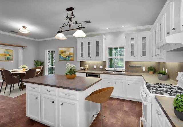 kitchen featuring dark countertops, white cabinetry, a kitchen island, and white gas range