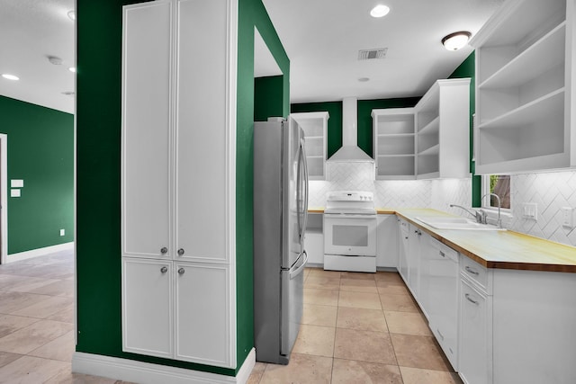 kitchen featuring white appliances, visible vents, white cabinets, wall chimney range hood, and open shelves