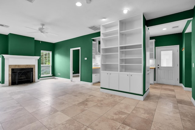 unfurnished living room with baseboards, ceiling fan, visible vents, and a tiled fireplace