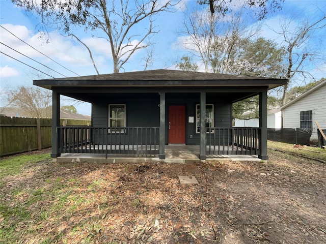 view of front of property featuring a porch, a shingled roof, and fence