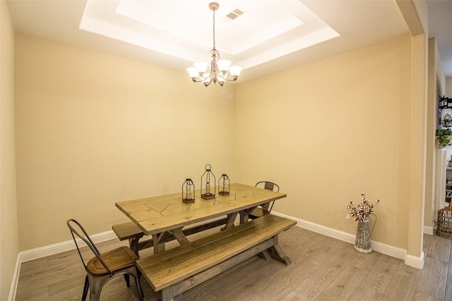 dining room with baseboards, visible vents, a raised ceiling, and wood finished floors