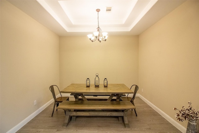 dining room featuring baseboards, visible vents, a raised ceiling, dark wood-style flooring, and a chandelier