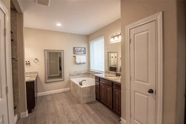 full bathroom featuring two vanities, visible vents, a sink, wood finished floors, and a bath