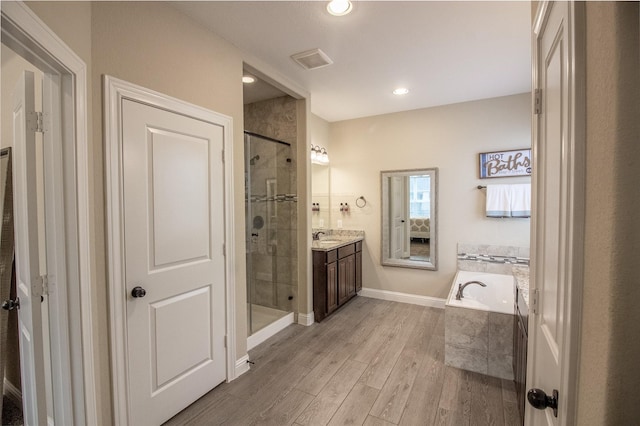 bathroom with a garden tub, wood finished floors, visible vents, vanity, and a stall shower