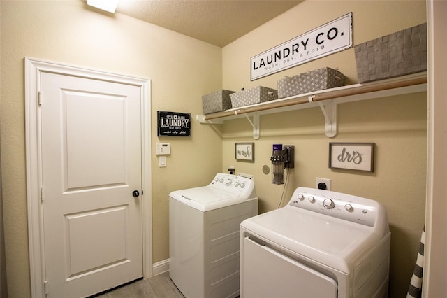 laundry room featuring a textured ceiling, laundry area, light wood finished floors, and independent washer and dryer