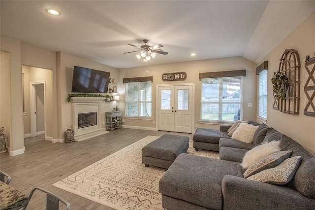 living room with a wealth of natural light, a fireplace with raised hearth, wood finished floors, and recessed lighting