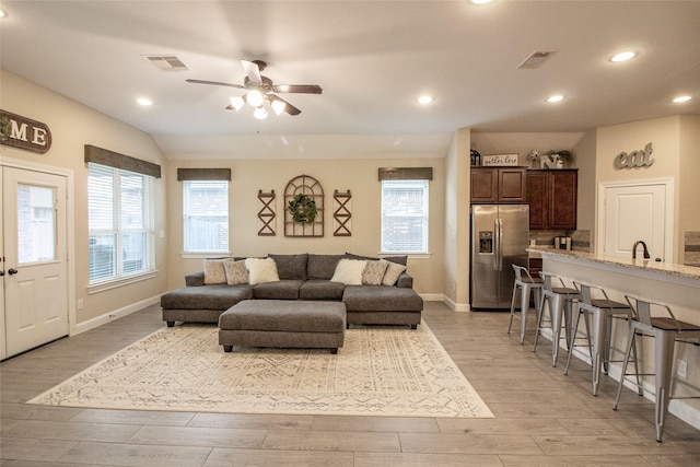 living room featuring visible vents, a wealth of natural light, light wood-style flooring, and a ceiling fan