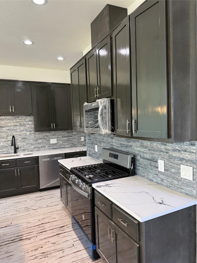 kitchen with recessed lighting, backsplash, appliances with stainless steel finishes, light wood-style floors, and a sink