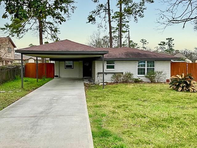 single story home featuring a carport, driveway, a front lawn, and fence