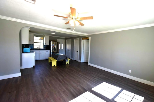 unfurnished living room with baseboards, a sink, dark wood finished floors, and crown molding