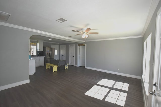 unfurnished living room with dark wood-style floors, arched walkways, visible vents, and crown molding