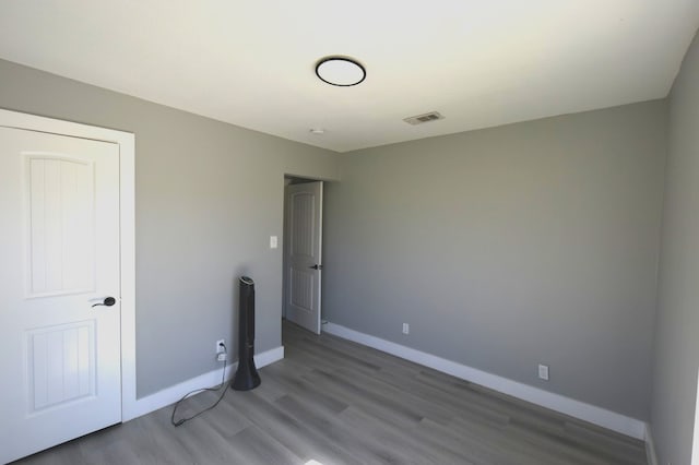 empty room with visible vents, baseboards, and wood finished floors