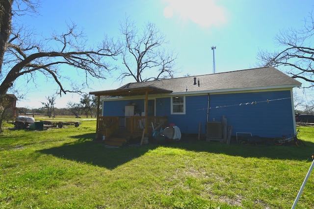 back of house featuring a shingled roof and a lawn