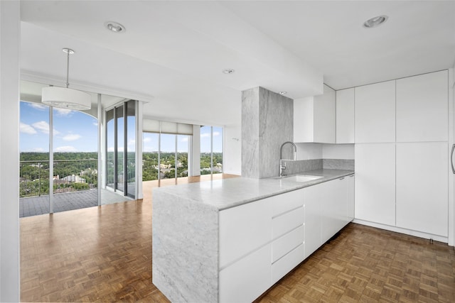 kitchen featuring a peninsula, a sink, white cabinets, light countertops, and modern cabinets