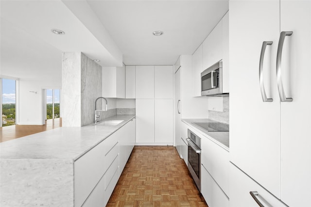 kitchen featuring stainless steel appliances, modern cabinets, a sink, and white cabinetry