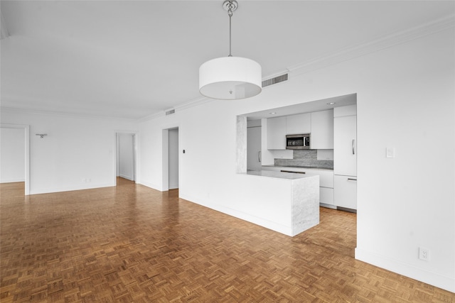 kitchen featuring stainless steel microwave, open floor plan, hanging light fixtures, light countertops, and white cabinetry