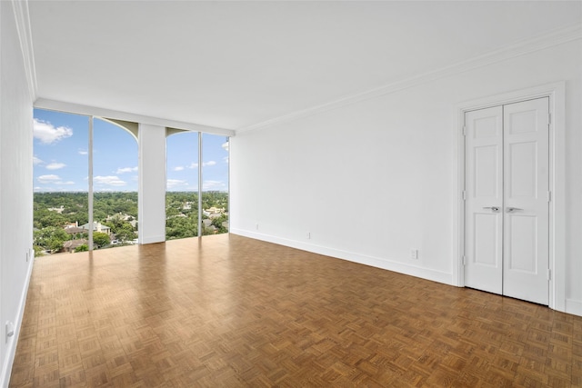 spare room with expansive windows, ornamental molding, and baseboards