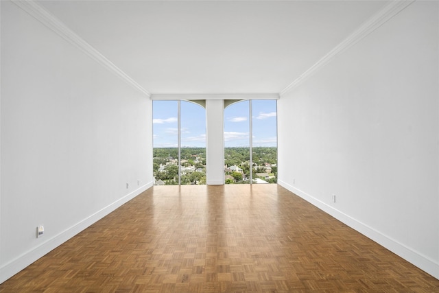 spare room featuring expansive windows, crown molding, and baseboards