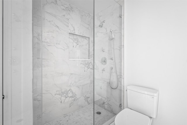 bathroom with toilet and a marble finish shower