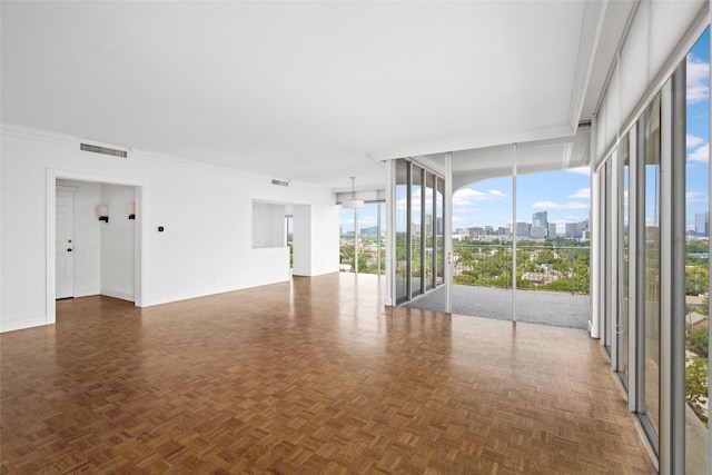 unfurnished room featuring baseboards, a view of city, visible vents, and crown molding