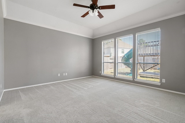 carpeted spare room featuring ceiling fan, baseboards, and crown molding