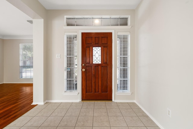 foyer with light tile patterned floors, visible vents, baseboards, rail lighting, and crown molding