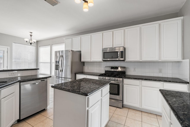 kitchen with light tile patterned floors, visible vents, appliances with stainless steel finishes, white cabinetry, and a kitchen island