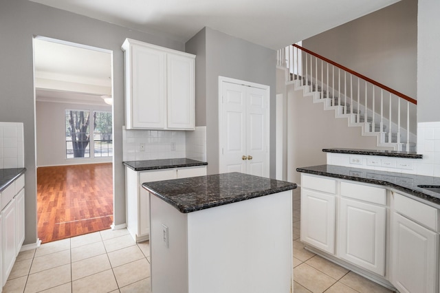 kitchen with light tile patterned floors, a kitchen island, white cabinetry, and backsplash