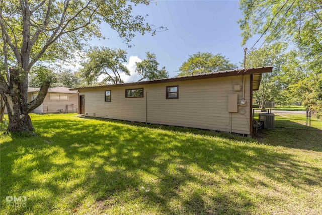 back of property featuring fence, central AC unit, and a yard