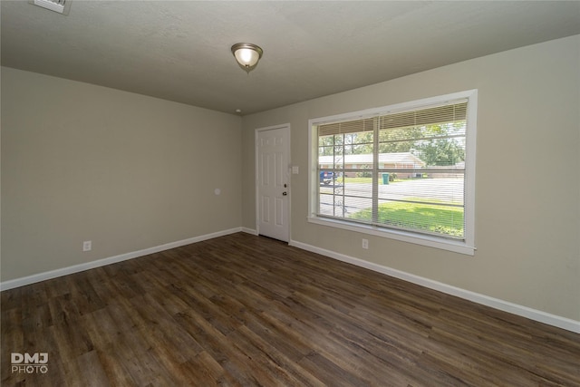 empty room featuring dark wood-style floors and baseboards