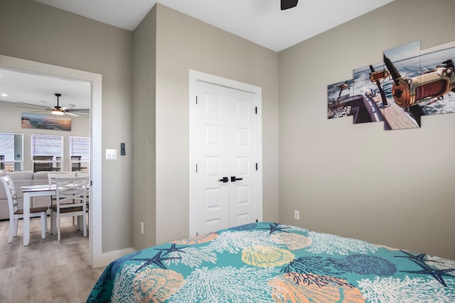 bedroom featuring ceiling fan, a closet, wood finished floors, and baseboards