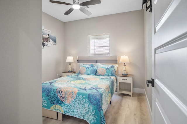 bedroom with light wood-type flooring, a ceiling fan, and baseboards