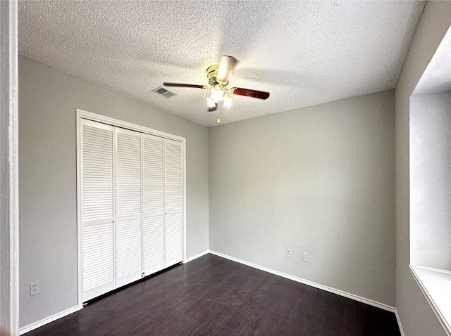 unfurnished bedroom featuring baseboards, visible vents, dark wood-style floors, ceiling fan, and a closet