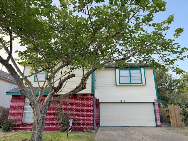 view of front of home with driveway, brick siding, an attached garage, and fence